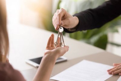 A luxury real estate agent hands over a set of house keys to a satisfied buyer